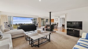 Un salon moderne avec une cheminée, un téléviseur et une vue sur la mer.