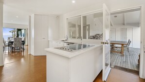 Une cuisine moderne avec des meubles blancs, un îlot central et un coin repas offrant une vue agréable.