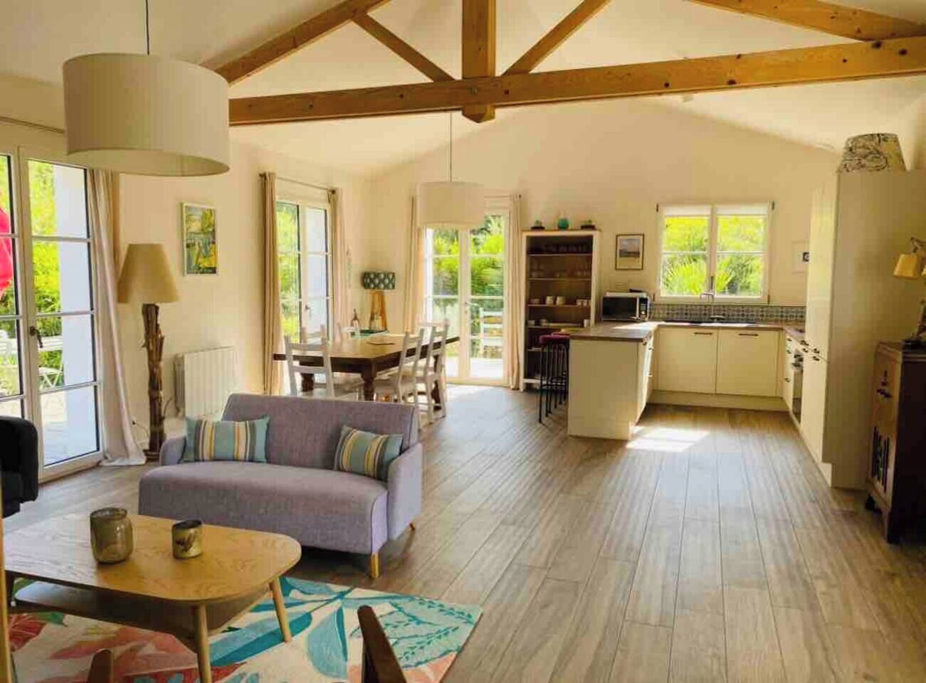 Un vaste espace de vie comprenant un canapé, une table à manger et une cuisine avec un bar.