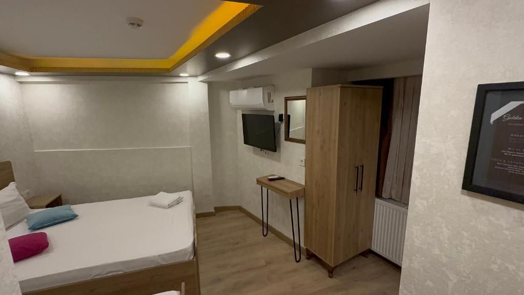 Una habitación de hotel con cama, una mesita, un armario y un televisor montado.