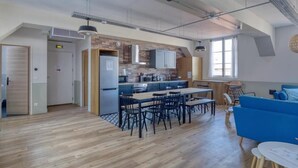 A modern kitchen with a central island, wooden flooring, and a dining area with black chairs. - PHILIPPE AUGUSTE LOFT 5 - Loft for 12 - 5 rooms - BASTILLE - PÈRE LACHAISE (Paris)