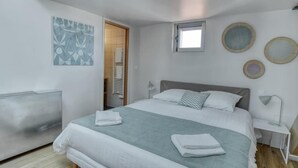 A modern bedroom with a large bed, a bedside table, a wall-mounted artwork, and a window. - PHILIPPE AUGUSTE LOFT 5 - Loft for 12 - 5 rooms - BASTILLE - PÈRE LACHAISE (Paris)
