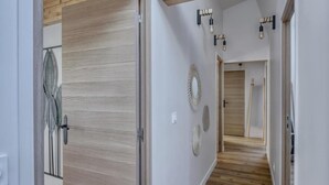 A hallway with wooden flooring, a light-colored wall, and a door with a leaf-patterned door handle. There are wall-mounted light fixtures and a mirror with a circular frame. - PHILIPPE AUGUSTE LOFT 5 - Loft for 12 - 5 rooms - BASTILLE - PÈRE LACHAISE (Paris)