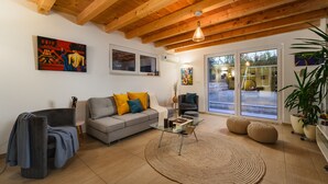 Una sala moderna con un sofá gris, una mesa de centro de vidrio y un techo de madera.