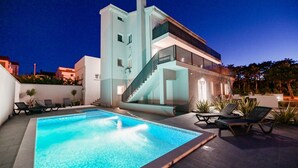 Ein modernes Gebäude mit Pool, Außenbereich und einer Treppe, die zu einer oberen Ebene führt.