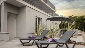Two lounge chairs with towels, a patio table, and a building with a modern design. - Modern apartment Lacrima 2 in villa with a pool on Krk (Silo)