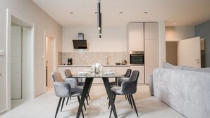 A modern kitchen with a dining area, featuring a marble countertop, built-in oven, and a pendant light above the table. - Modern apartment Lacrima 2 in villa with a pool on Krk (Silo)