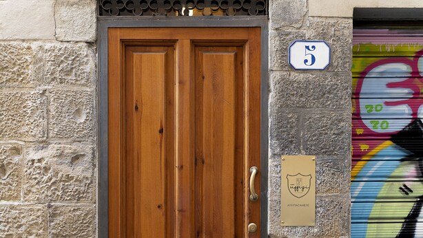 A wooden double door with a metal frame, a stone wall, and a number sign indicating the address. - Casa Uffizi Tower House Boutique Hotel (Florence)
