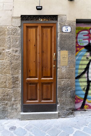 Puerta doble de madera con marco de metal, pared de piedra y un cartel con el número de la dirección.
