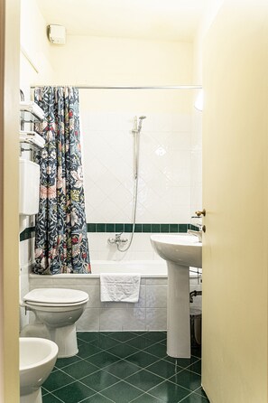 A bathroom with a bathtub, two toilets, a sink, and a shower. - Casa Uffizi Tower House Boutique Hotel (Florence)