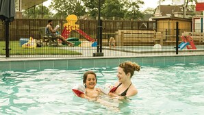 A swimming pool with a child and an adult.
