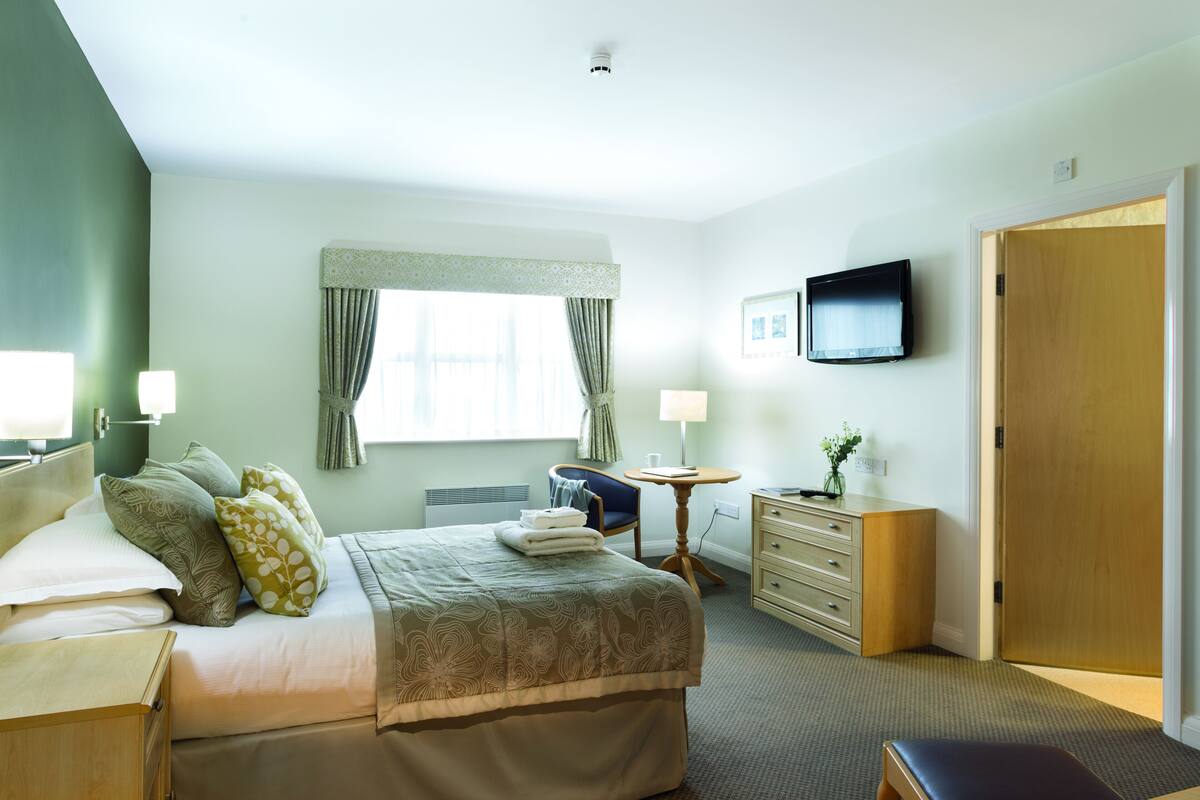Une chambre d’hôtel comprenant un lit, des tables de chevet, un bureau, une chaise, une télévision et une armoire.