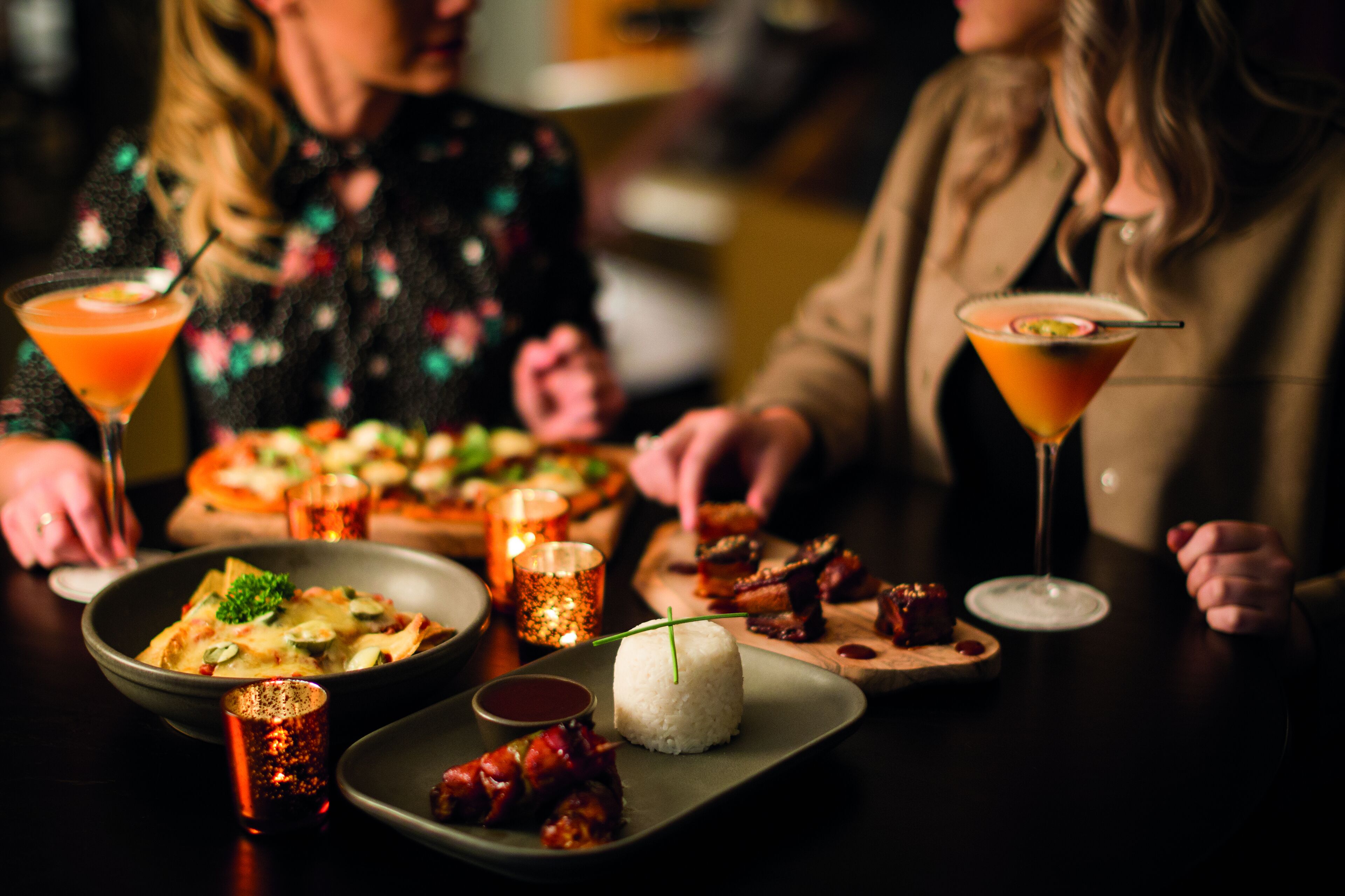 Una mesa de comedor con diferentes platos, bebidas y una vela.