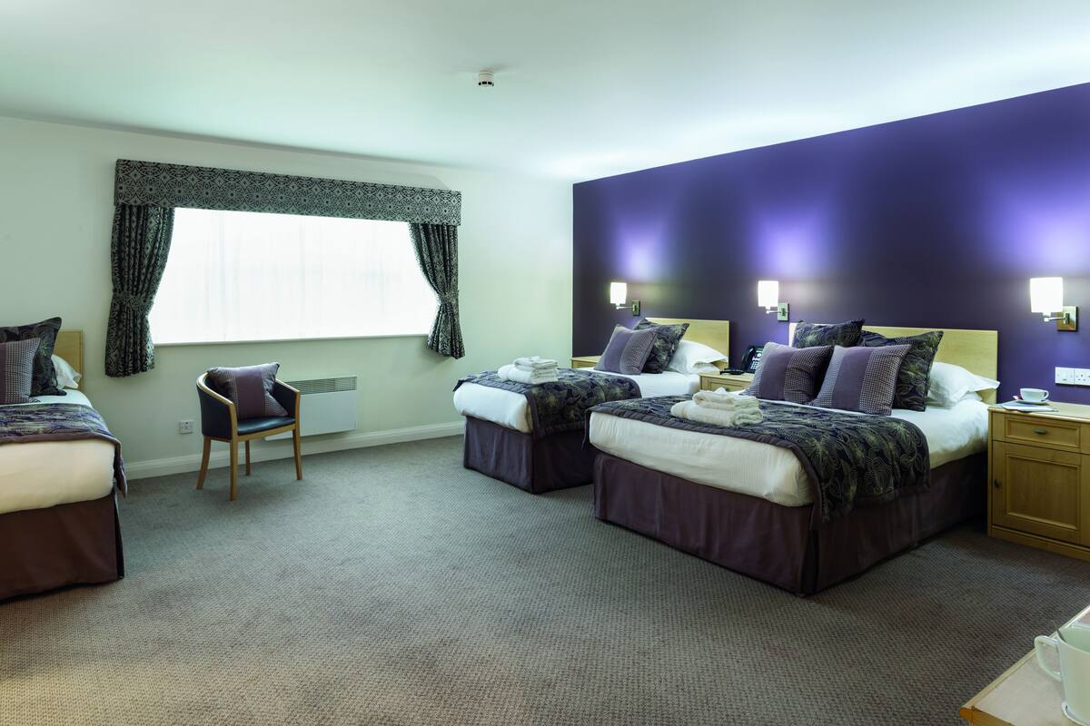 Une chambre d’hôtel avec deux lits, une chaise et une petite table.