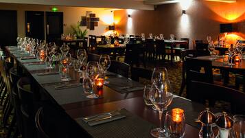 A restaurant with long tables set for dining, candles, and a warm ambiance.