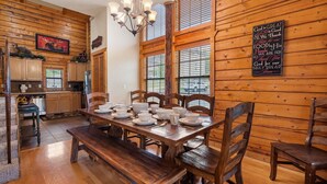 A wooden interior with a dining table set for four, wooden walls, a chandelier, and a sign with a religious message. - Rustic-Chic 4BR + Loft Cabin | Golf & Show Discounts! (Branson)