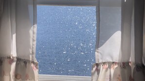 A window with a view of a clear blue sky and a distant treeline.