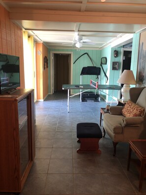 Relax in this spacious living area with a high ceiling, featuring a comfortable sofa, TV, and treadmill.