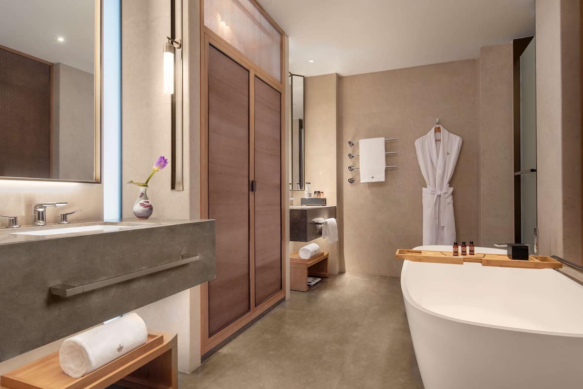 Un baño moderno con una bañera grande, un tocador con espejo y una ducha a pie.
