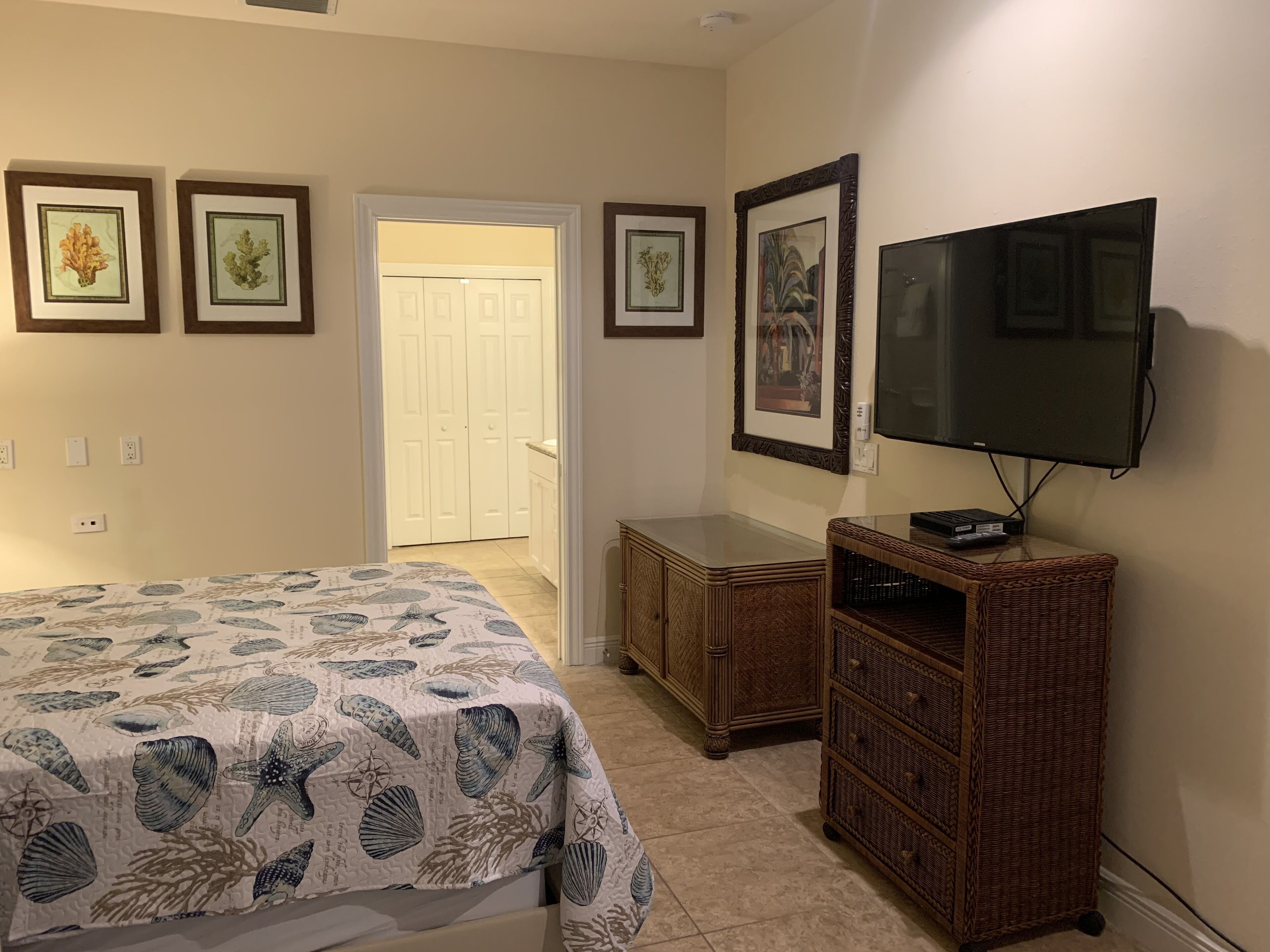 Une chambre à coucher avec un lit, une télévision, une commode et des tableaux encadrés accrochés au mur.