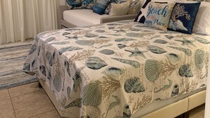 Een slaapkamer met een bed, een slaapbank, een plafondventilator en een schilderij aan de muur.