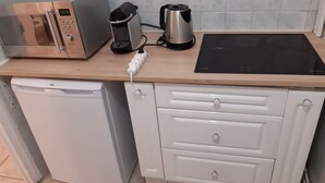 Eine kompakte Küche mit Mikrowelle, Toaster, Wasserkocher und einem kleinen Geschirrspüler.