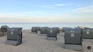Beach chairs arranged in rows on a sandy beach with a clear view of the ocean. - Refugium 2 (Kellenhusen)