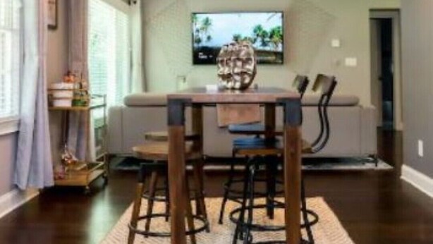 Un comedor con una mesa y sillas de madera, un televisor montado en la pared y un ventilador de techo.