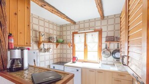 A compact kitchen with wooden cabinets, a coffee maker, a kettle, and a dishwasher.