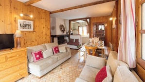 A cozy wooden interior with a sofa, TV, and a dining area.