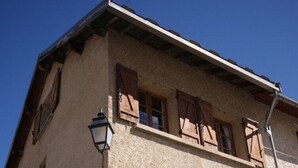 A two-story building with wooden shutters, a sign reading 'Maison Mignon,' and a small window.