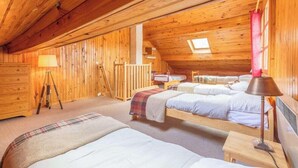 A cozy attic bedroom with wooden walls, a skylight, and two beds.