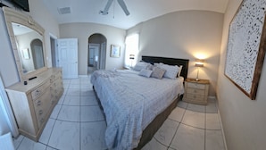 Ein Schlafzimmer mit Bett, Schminktisch, Spiegel und einer Wand mit dekorativer Verkleidung.