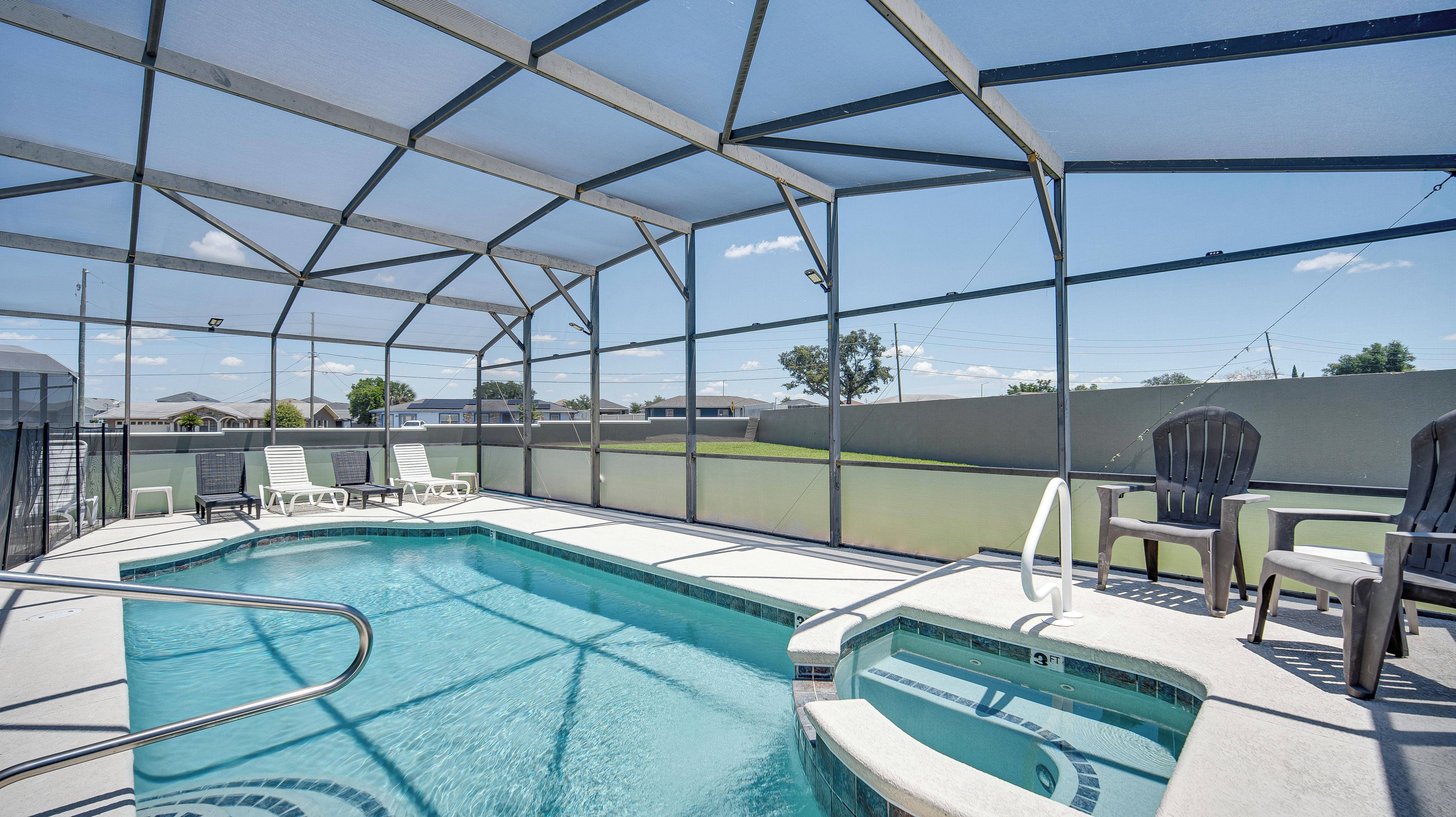 A covered outdoor swimming pool with lounge chairs and a view of the surrounding area.
