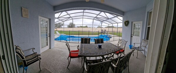 A covered patio with a pool, outdoor furniture, and a view of the pool area.