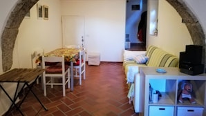 A cozy room with a dining table, chairs, a sofa, and a small cabinet. - Casa nel Borgo di Santa Fiora (Santa Fiora)