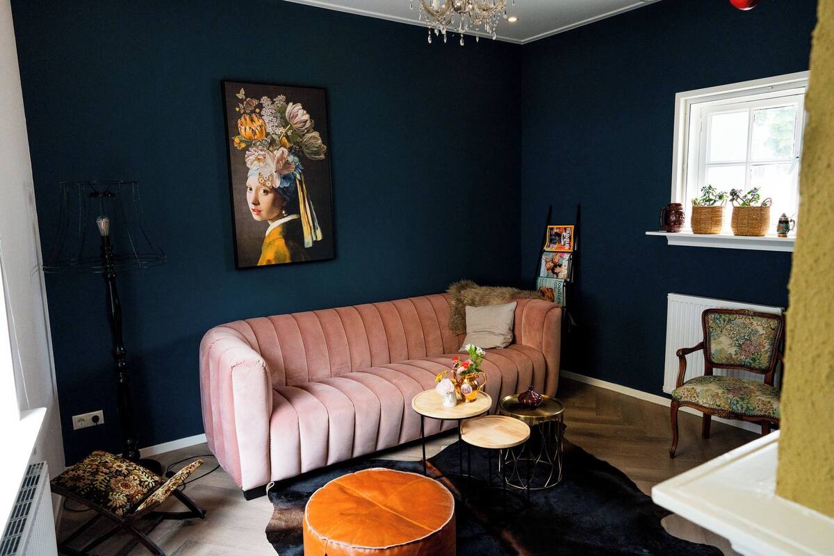 Una sala de estar acogedora con un sofá rosa, una mesa de centro redonda y una araña.
