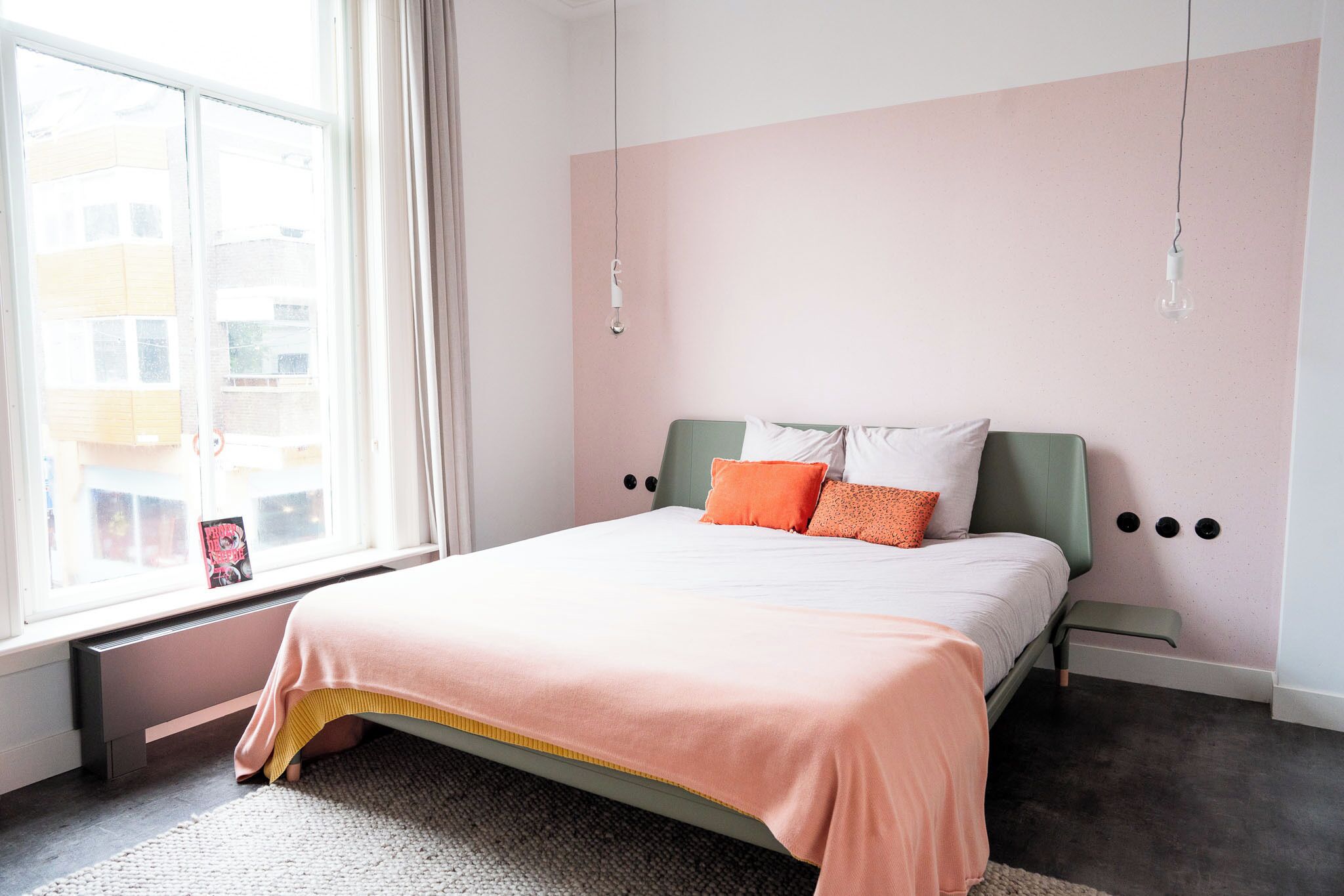 Ein Schlafzimmer mit Bett, Fenster und Heizkörper.