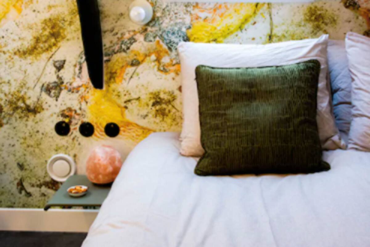 Una cama con un almohadón verde, un almohadón blanco y una colcha blanca.