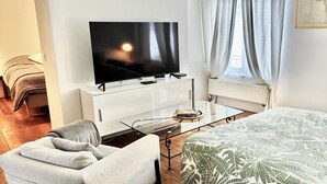 A modern hotel room with a bed, a TV, a glass coffee table, and a sofa. - Comfortable 1 bedroom - Fully equipped kitchen - Brussels center (Bruxelles)