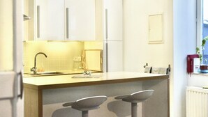 A modern kitchen with white cabinets, a central island with stools, a built-in oven, and a window with a view of the outdoors. - Comfortable 1 bedroom - Fully equipped kitchen - Brussels center (Bruxelles)