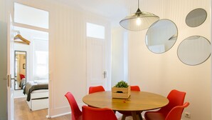 Un comedor con una mesa redonda de madera, sillas rojas y una lámpara colgante.