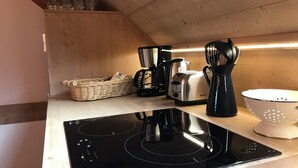 Une cuisine moderne équipée d’une plaque de cuisson à induction noire, d’un grille-pain, d’une machine à café et d’une passoire.