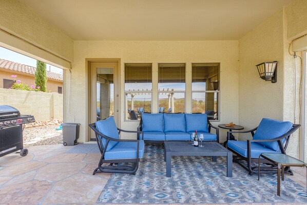 A covered patio with a blue sofa, two armchairs, a small table, and a grill. - Heated Pool*/Spa, Mountain/Sunset Views, Amenities Galore.... (Phoenix)