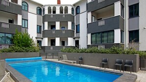 Un bâtiment moderne doté d’une piscine, d’un espace extérieur aménagé et d’un jardin bien entretenu.