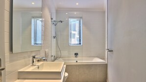 Une salle de bain moderne avec un double vasque, une baignoire et une douche.