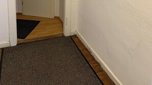 A hallway with a door, a doormat, and three paintings on the wall.