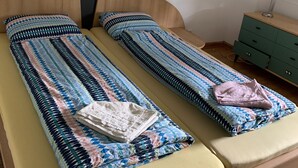 A double bed with a patterned bedspread, a bedside table with a lamp, and a green dresser.