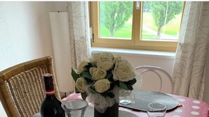 Et spisebord dækket med servietringe, bestik, en vinflaske, et glas og en vase med hvide blomster.