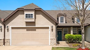 A two-story house with a beige exterior, a large garage door, and a green door. - Branson Vacation Rental | Game Room | Garage | Sleeps 8 (Branson)